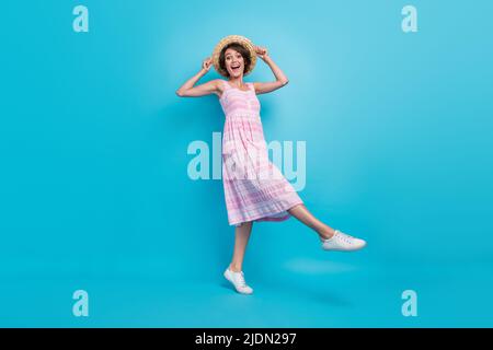 Foto a tutta lunghezza di funky giovane donna andare indossare cappello lungo sarafan isolato su sfondo blu Foto Stock