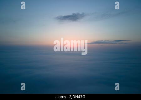 Vista aerea dall'alto ad alta quota di dense nuvole di cumulo puffy volare in serata. Incredibile tramonto dal punto di vista della finestra dell'aeroplano Foto Stock