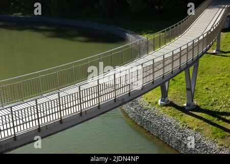 Ponte pedonale sull'acqua. Ponte con ringhiere. Dettagli del parco in città. Argine sul lago. Foto Stock