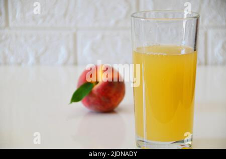 Succo di pesca fresco in bicchiere su sfondo bianco. Foto Stock