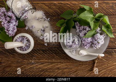 un ramo di lilla da giardino, petali, zucchero in un vaso di vetro sparso sul tavolo. il concetto di zucchero floreale fatto in casa Foto Stock