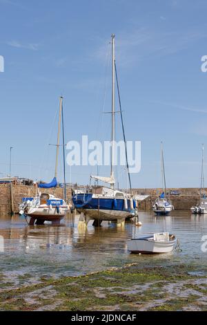 Paignton, Devon, UK, maggio 14th 2022: All'interno delle mura di Paignton Harbor gli yacht ormeggiati riposano sulla sabbia a bassa marea sotto un cielo blu. Foto Stock