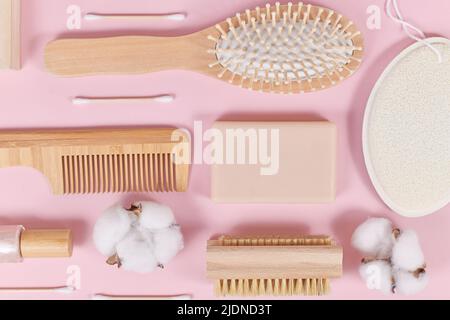Prodotti ecologici per la bellezza e l'igiene del legno come pettine e sapone su sfondo rosa Foto Stock