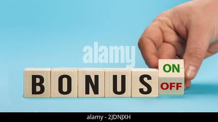 Il bonus sta salendo o morendo. Mano sta girando i cubi di legno un dado e cambia la direzione di una freccia che simboleggia che il bonus sta andando verso l'alto o. Foto Stock