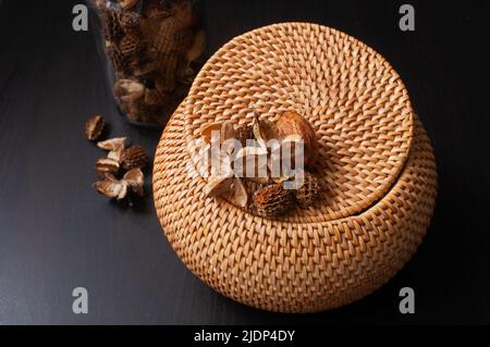 wicker scatola di paglia artigianale top rotondo con fiori secchi e lavanda su sfondo nero Foto Stock
