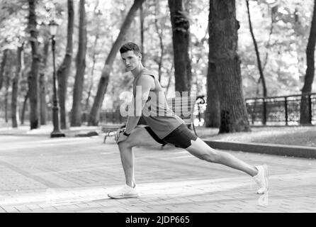 Riscaldamento prima dell'allenamento. Montare il ragazzo in posizione di affondo. L'uomo fa esercizi di riscaldamento. Attività di riscaldamento Foto Stock