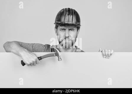 operaio sopportato in hardhat dietro foglio di carta giallo. annuncio del lavoratore di pubblicità Foto Stock