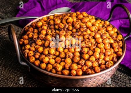 Sumac e ceci arrosto con spezie: Fagioli di garbanzo arrostiti serviti in un piatto di rame balti martellato Foto Stock