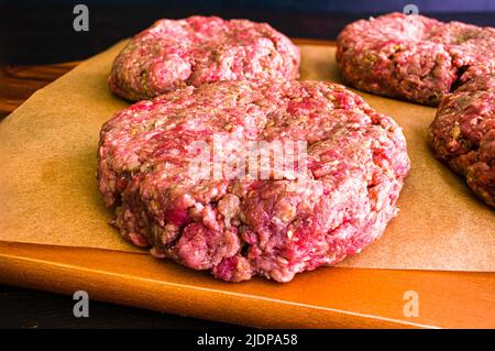 Hamburger crudo condito con pesto e aglio: Primo piano vista di hamburger fatti a mano con condimenti italiani Foto Stock