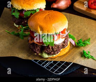 Tuscano Burger con mozzarella, panchetta e Aioli al basilico: Hamburger all'italiana con formaggio fuso, rucola, pomodoro e pancetta fritta Foto Stock