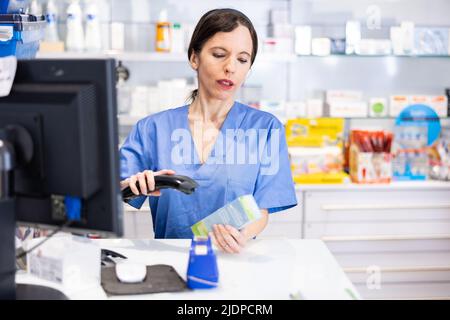 Ritratto di donna farmacista utilizzando il lettore di codici a barre su medicina Foto Stock