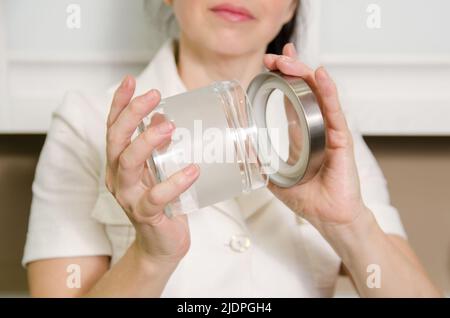 La donna chiude il coperchio del vaso di vetro vuoto che tiene in mano Foto Stock