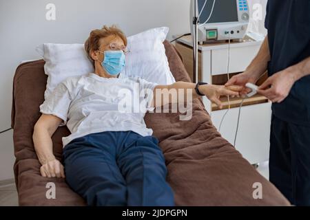 Controllo del personale infermieristico con la saturazione di ossigeno pulsossimetrica del sangue del paziente in ospedale Foto Stock