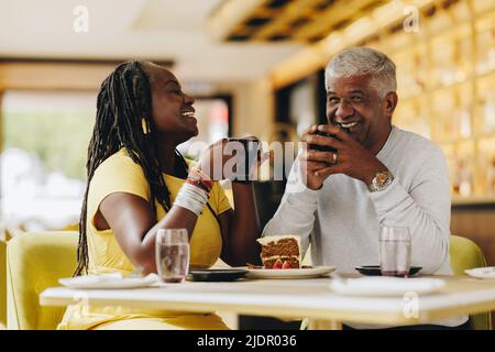 Una coppia felice che ride allegro mentre si fa un caffè insieme in un bar. Spensierate la coppia anziana che si è recata bene in un ristorante. Colpo di Stato maturo Foto Stock