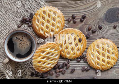 Tazza di caffè e biscotti con ripieno di mele, su sfondo di legno, vista dall'alto Foto Stock