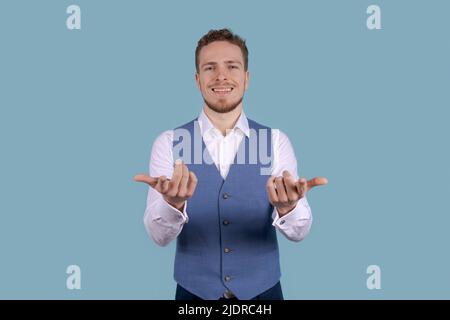 WOW questo è incredibile. Scioccato uomo d'affari caucasico sorridente puntando da parte il gesto nello spazio copia indossando camicia bianca e getto blu su sfondo blu Foto Stock