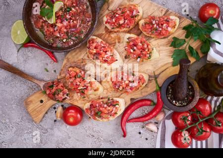 gustosi spuntini salsa bruschetta nella cucina domestica su tagliere in legno Foto Stock