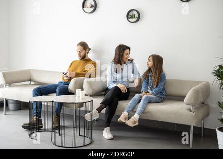 Giovani seduti sul divano nella sala d'attesa della clinica Foto Stock
