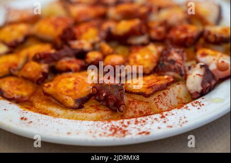 Gustosi frutti di mare, polpo alla griglia in stile galiziano con paprika pimento rosso e patate serviti nel ristorante spagnolo Foto Stock