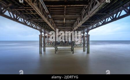 La fotografia a lunga esposizione cattura la parte inferiore del molo centrale a Blackpool, Lancashire, Regno Unito, in alta marea con il mare che guarda liscio e sfocato Foto Stock