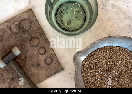 Scrivania per la produzione artigianale di gioielleria con strumenti professionali. Tavolo in legno grunge. Vista dall'alto. Foto Stock