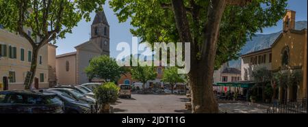 Panorama della piazza del villaggio di un villaggio di montagna nelle Alpi inferiori della Provenza, Francia con municipio, una chiesa e un ristorante. Foto Stock
