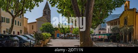 Panorama della piazza del villaggio di un villaggio di montagna nelle Alpi inferiori della Provenza, Francia con municipio, una chiesa e un ristorante. Foto Stock