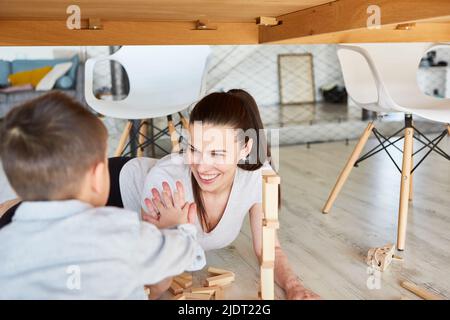 Mamma e figlio giocano con i blocchi di costruzione insieme nel soggiorno e danno alto cinque Foto Stock