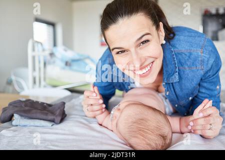 Felice madre sorridente che tiene il bambino sul tavolo cambiante per maternità e amore materno Foto Stock