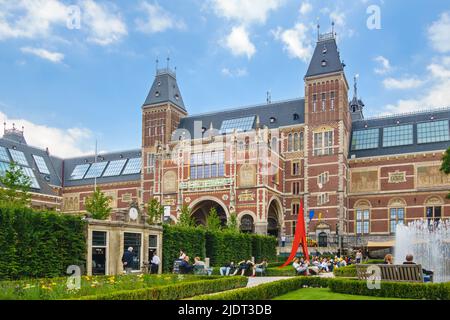 AMSTERDAM, PAESI BASSI - 26 GIUGNO 2014: Vista al Rijksmuseum con i turisti seduti nel giardino del museo di Amsterdam, Paesi Bassi Foto Stock