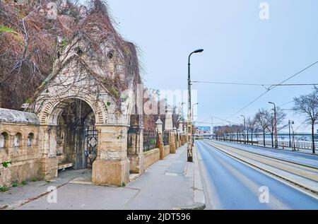 Szent Gellert Rakpart (Quay di San Gellert) con vista su edifici storici in pietra della Cappella rupestre del Monastero Paolino, Budapest, Ungheria Foto Stock