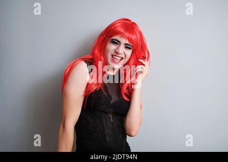 Ritratto di sesso maschile fluido vestito come femmina ridendo e guardando la fotocamera. Foto Stock