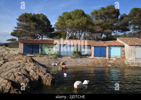 Colorato Old Boatsheds sulla riva vicino alla spiaggia o Plage de Bregancon di fronte Breganon Fort & Island Bormes-les-Mimosas Var Provence france Foto Stock