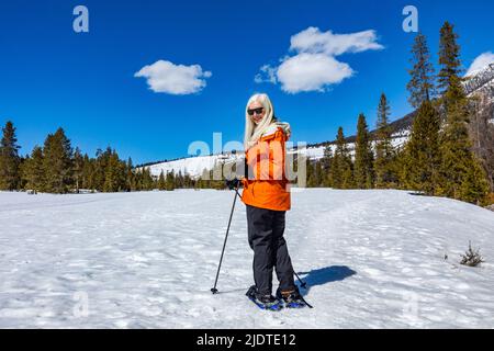 USA, Idaho, Ketchum, donna bionda anziana con racchette da neve in un paesaggio innevato Foto Stock