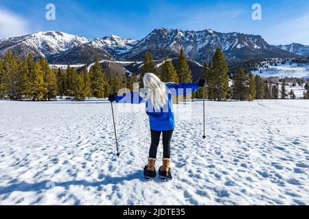 USA, Idaho, Ketchum, Vista posteriore della donna bionda anziana con racchette da neve nel paesaggio Foto Stock