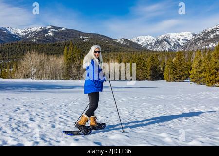 USA, Idaho, Ketchum, Ritratto di una donna bionda anziana che fa racchette da neve in un paesaggio innevato Foto Stock