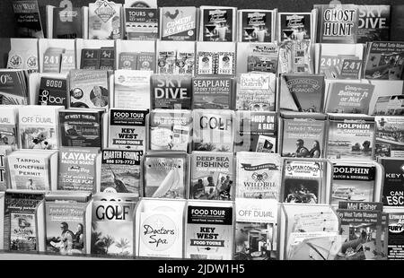 Opuscoli pubblicitari turistici presso l'edificio dell'Aeroporto Internazionale di Key West. Pile di opuscoli verticali per varie destinazioni o attività. Foto Stock