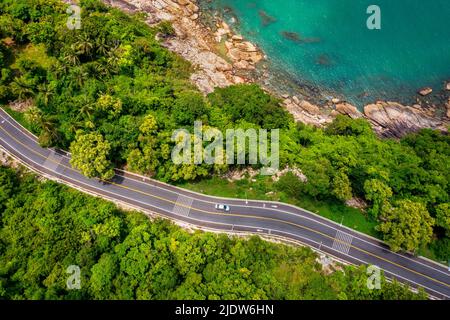 Vista aerea della strada tra palme da cocco e il grande oceano di giorno a Nakhon si Thammarat, Thailandia Foto Stock