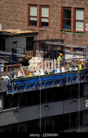 Lavoratori edili in alto sopra una strada urbana a New York City in un paniere sospeso, Midtown Manhattan, USA 2022 Foto Stock