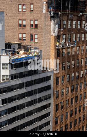 Lavoratori edili in alto sopra una strada urbana a New York City in un paniere sospeso, Midtown Manhattan, USA 2022 Foto Stock