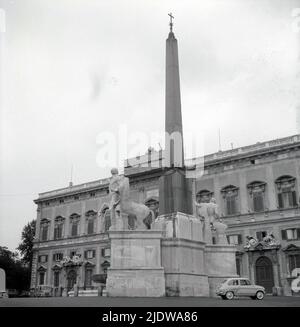 1950s, storica, alta colonna di pietra con croce religiosa cristiana in cima con stature di centurioni e cavalli alla base, Napoli, Italia. Fiat 500 auto parcheggiata accanto. Foto Stock