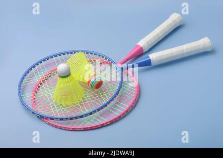 Coppia di racchette e shuttlecocks badminton su sfondo blu Foto Stock