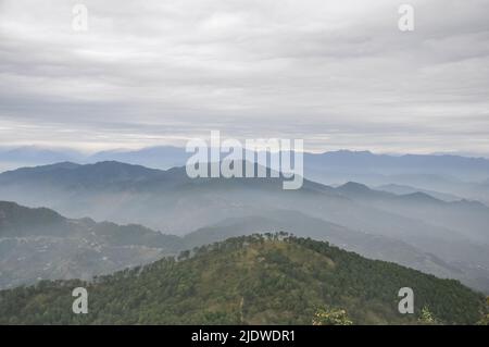 Splendidi strati di montagne ricoperti di nebbia in condizioni di nuvoloso tempo dopo la pioggia Foto Stock