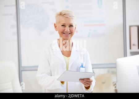 Ritratto di allegro neurologo femminile bello in camice da laboratorio utilizzando tablet digitale alla conferenza medica Foto Stock