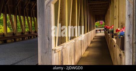 attraverso uno storico ponte coperto lungo la passerella pedonale con fioriere in fiore Foto Stock