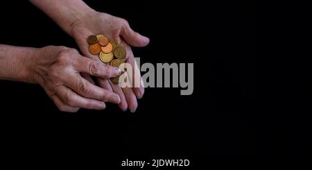 Le mani delle donne si avvicinano contando le monete nelle palme. Copia incolla, sfondo nero Foto Stock