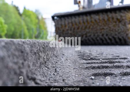 Pulizia dei rifiuti dalla strada. Una spazzola meccanica rotante Foto Stock