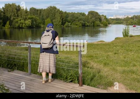 Mosca, Russia - 18 giugno 2022: Una donna anziana con uno zaino si erge nel parco . Foto di alta qualità Foto Stock