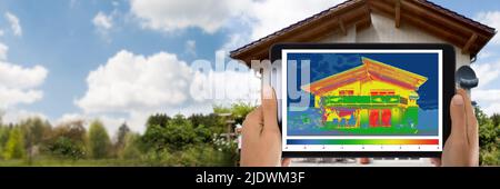 Close-up di persona a rilevare la perdita di calore al di fuori della casa usando la tavoletta digitale Foto Stock