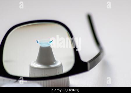La lente a contatto blu attraverso gli occhiali neri mostra occhiali diversi per correggere la lungimiranza e la miopia da optometria o occhio medico miopia Foto Stock